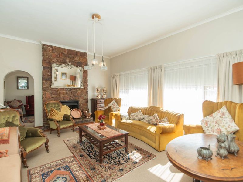 A spacious living room featuring a prominent stone fireplace, arched doorway, and large windows allowing for ample natural light.
