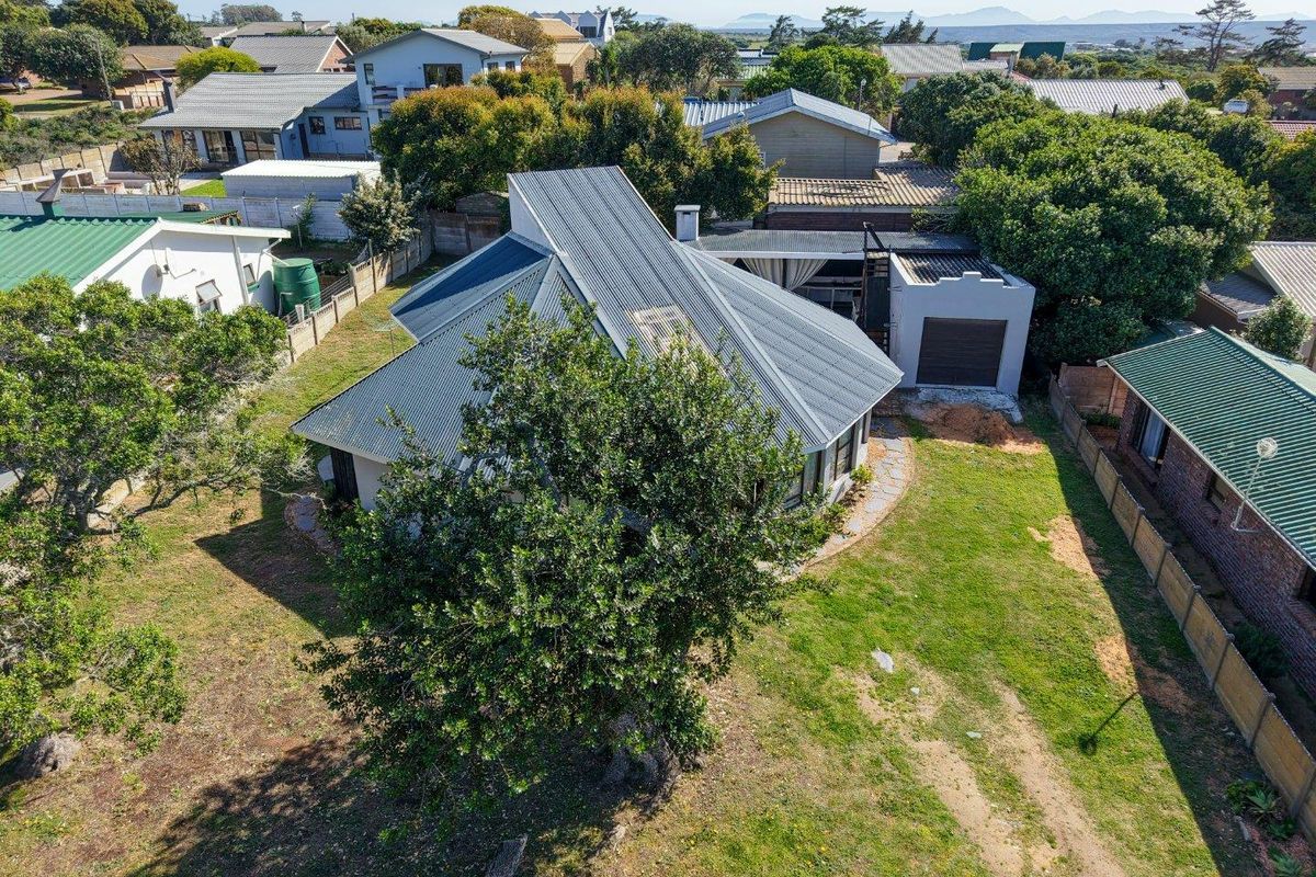 Aerial view of a residential property featuring a corrugated metal roof, a detached garage, and a spacious garden area within a suburban neighborhood.