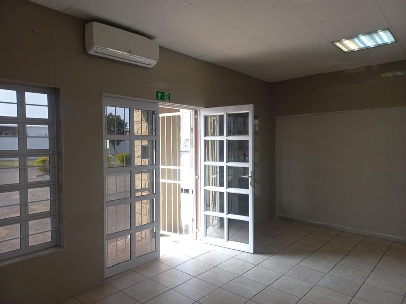 A vacant office space featuring tiled flooring, air conditioning, and secure glass-panelled entry doors with security gates.