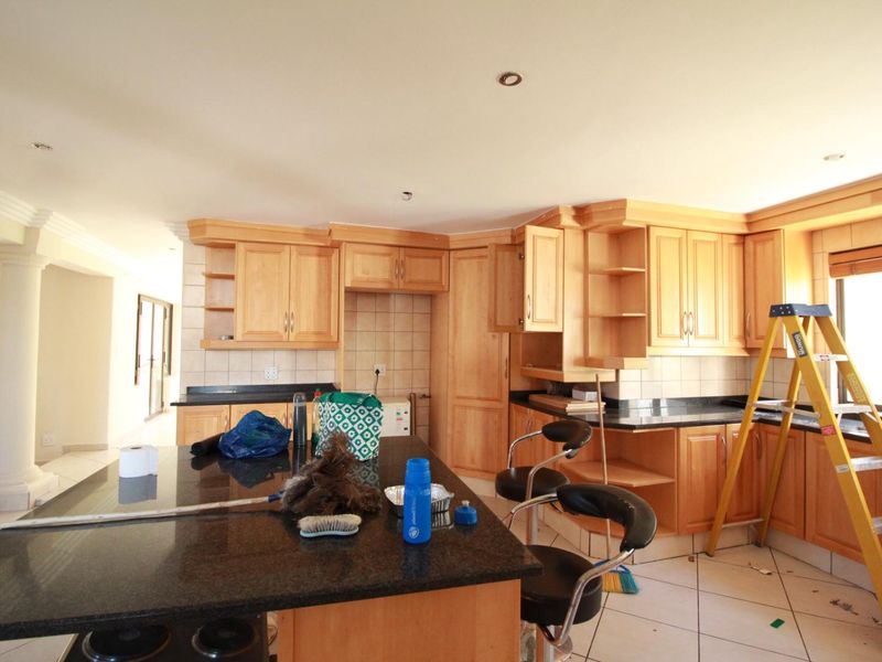 A spacious kitchen featuring wooden cabinetry, granite countertops, and a central island, offering a functional layout with potential for modern updates.