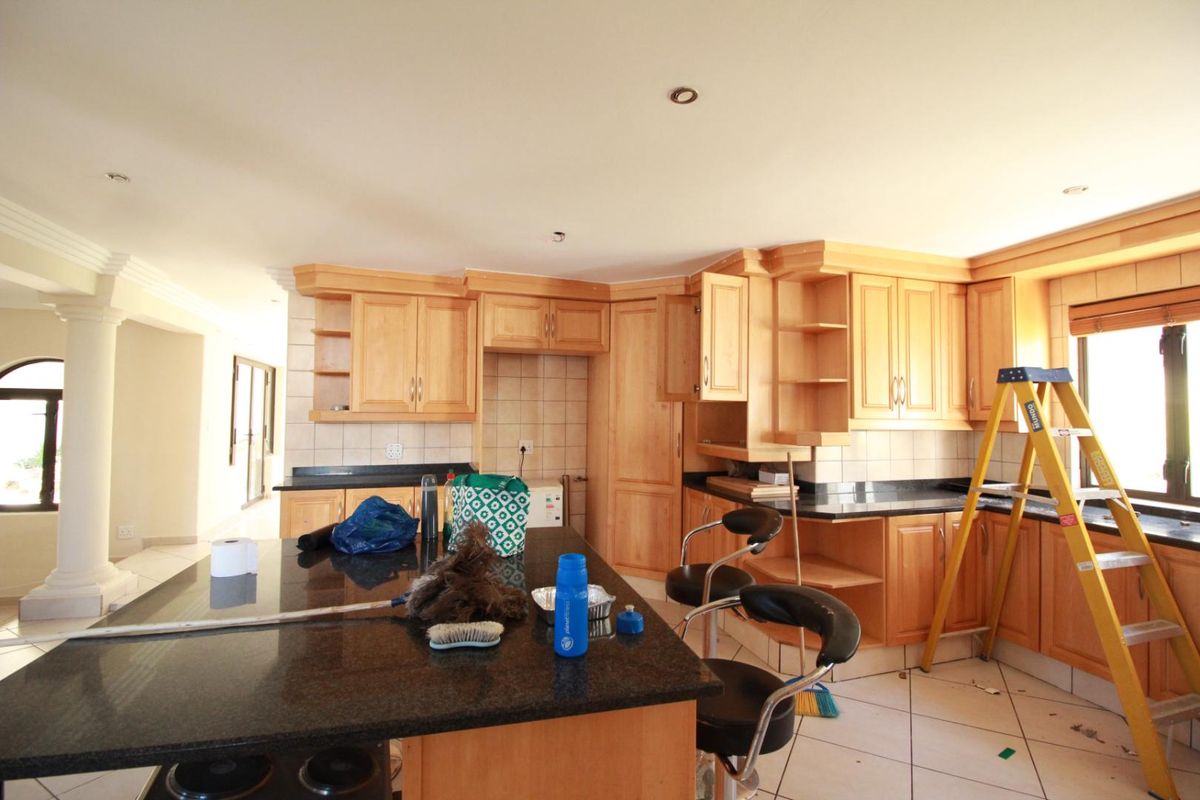 A spacious kitchen featuring wooden cabinetry, granite countertops, and a central island, offering a functional layout with potential for modern updates.