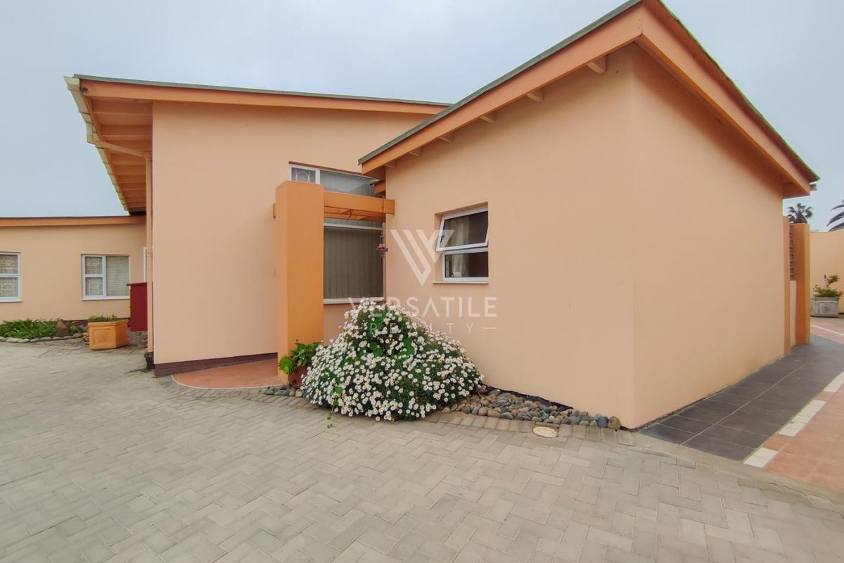 Exterior view of a retirement village unit featuring a paved driveway, peach-toned facade, and aluminium window frames.