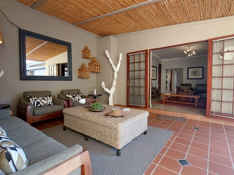 A covered patio featuring terracotta tile flooring and a bamboo ceiling, providing seamless indoor-outdoor flow through timber-framed glass doors.