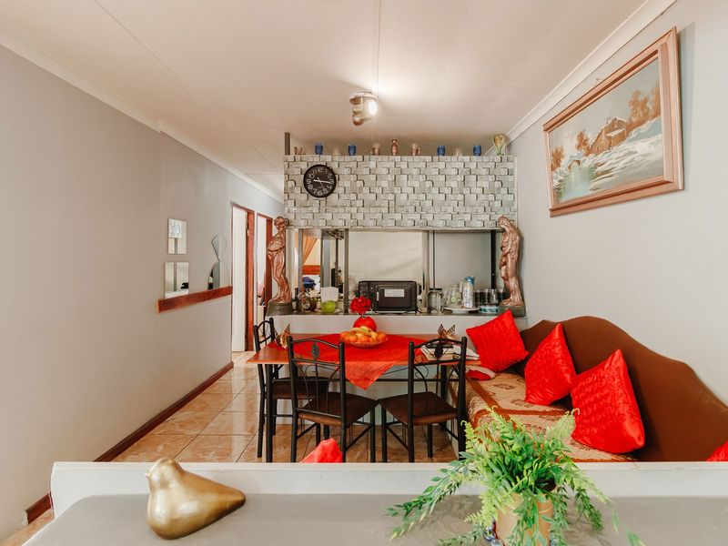 Open plan living and dining area featuring tiled flooring and a decorative brick partition wall with a convenient pass-through to the kitchen.