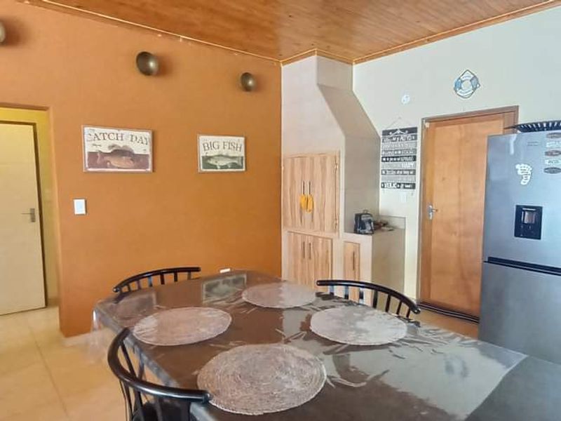 Open-plan living and kitchen area featuring tiled flooring, wooden ceiling, and built-in cabinetry, offering a functional space with potential for modern updates.