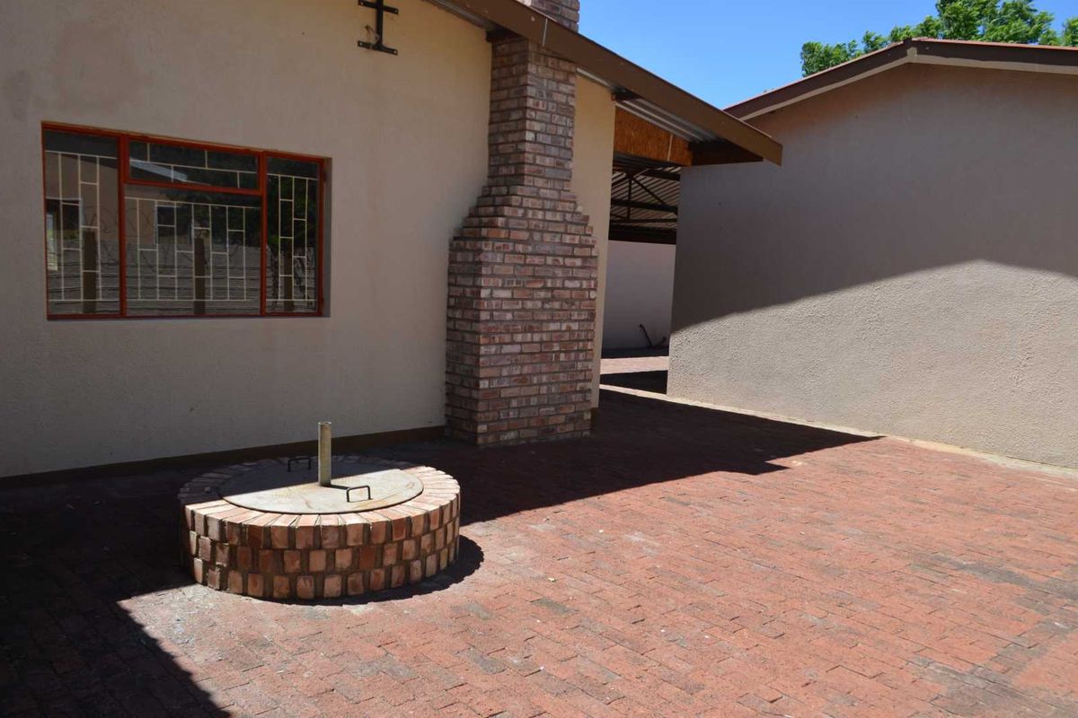 A paved rear courtyard area featuring a brick chimney stack and a circular brick-enclosed utility feature.