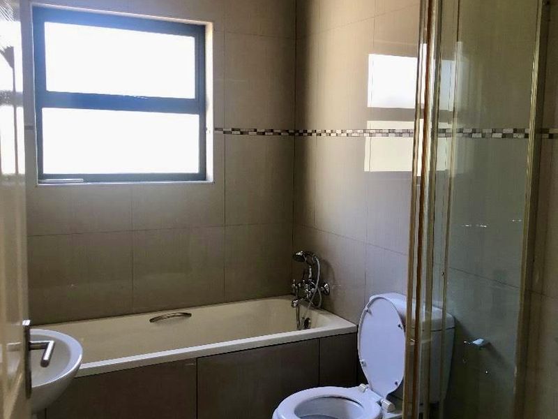 A functional bathroom featuring a built-in bathtub, a separate shower enclosure, and neutral wall and floor tiling.