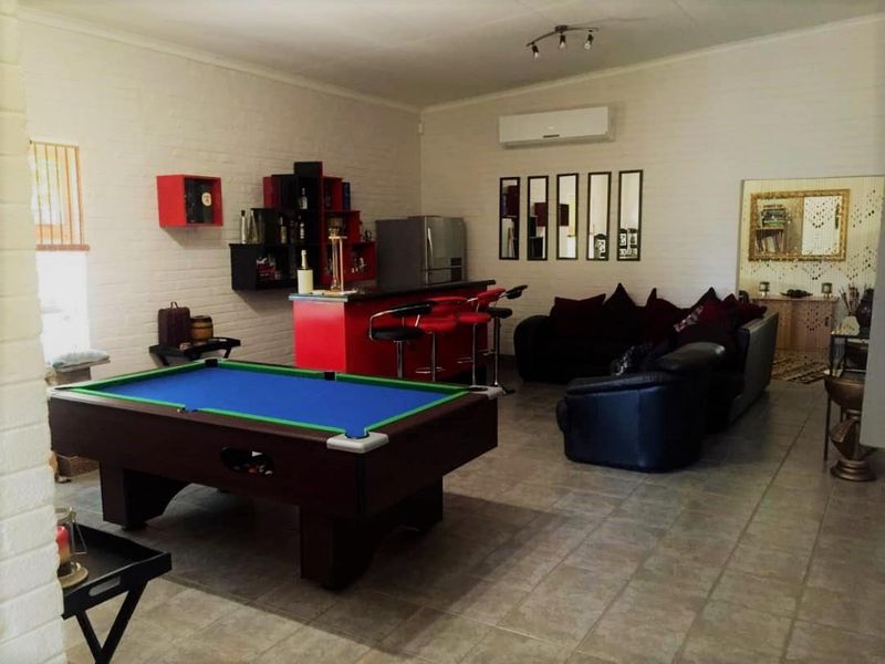 Spacious entertainment room featuring a built-in bar area, tiled flooring, and wall-mounted air conditioning unit.
