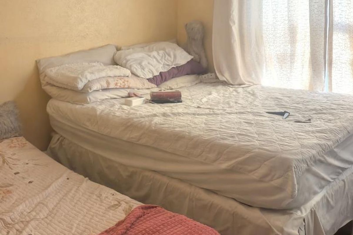 A bedroom featuring tiled flooring and large windows with curtains, providing natural light to the space.