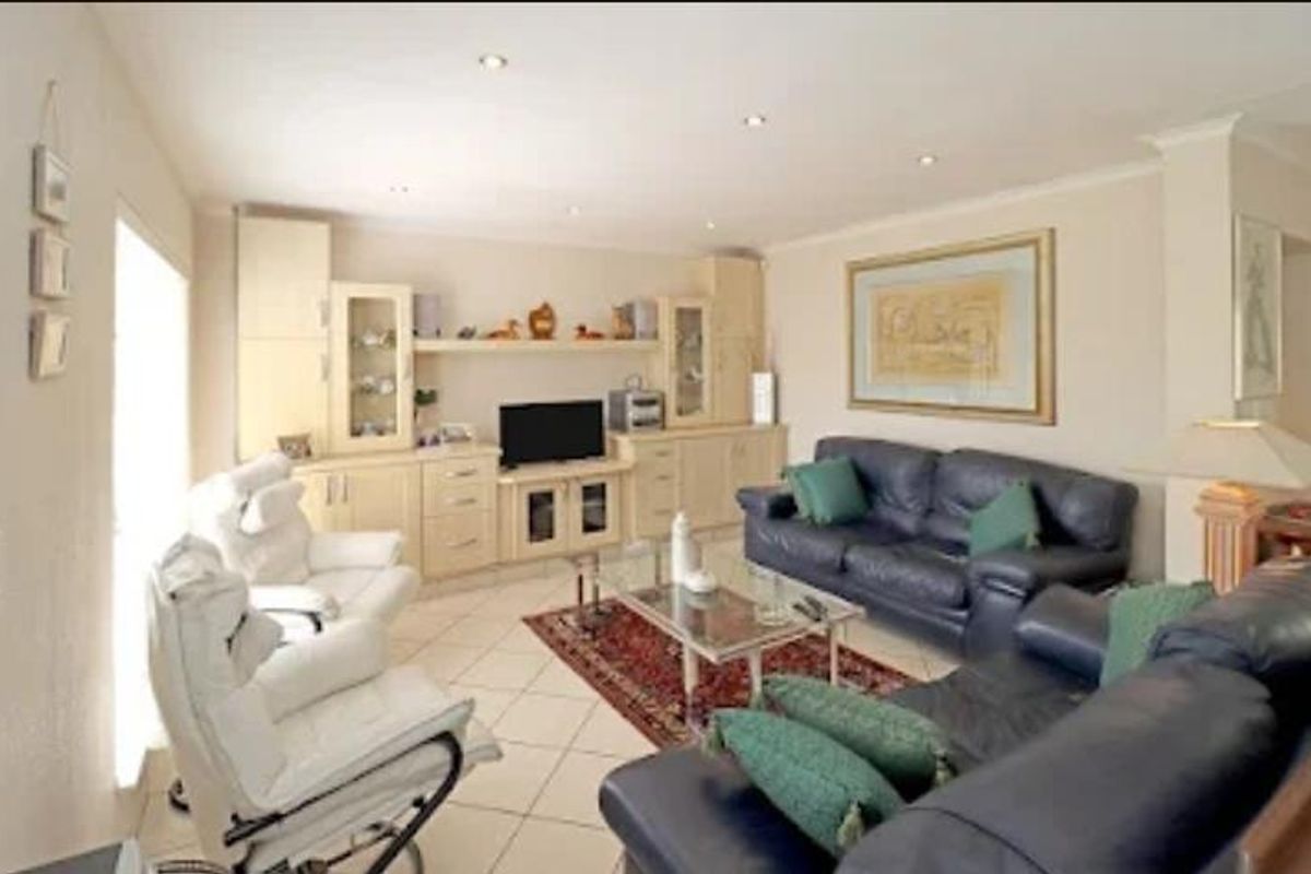 A comfortable living room featuring built-in cabinetry, tiled flooring, and recessed ceiling lighting, creating a functional and well-lit space.