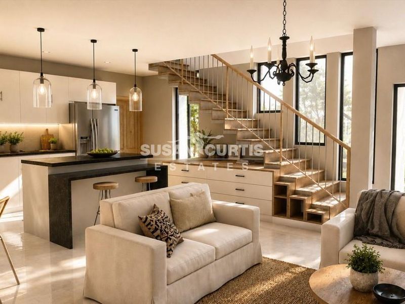 Modern open-plan living area featuring a sleek kitchen with island, integrated staircase with timber treads, and large glass doors leading to the exterior.