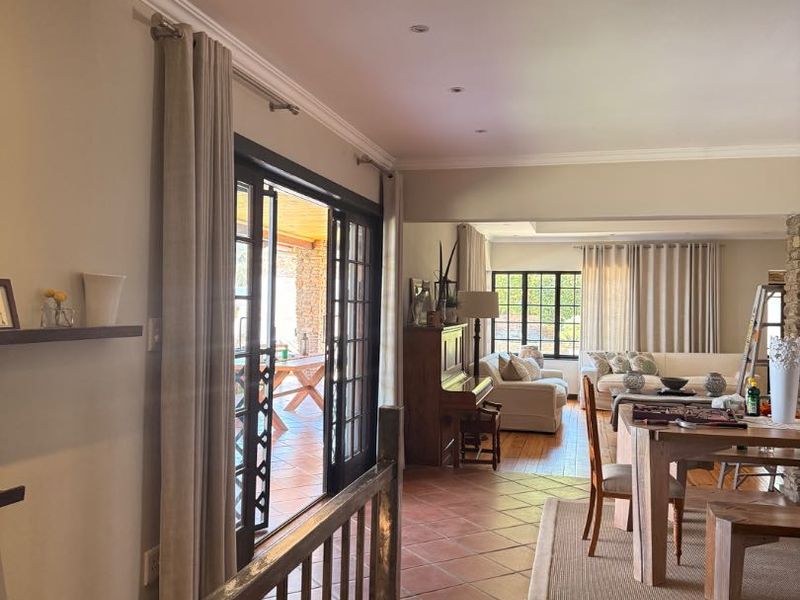 Spacious open-plan living and dining area featuring terracotta floor tiles, recessed lighting, and direct access to an outdoor patio through sliding glass doors.