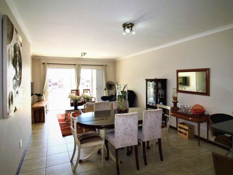 An open-plan living and dining area featuring tiled flooring, neutral walls, and a sliding glass door providing access to an outdoor space.