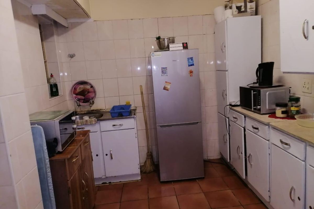 A compact kitchen featuring dated cabinetry, tiled splashbacks, and tiled flooring, offering potential for modernization and improved layout efficiency.