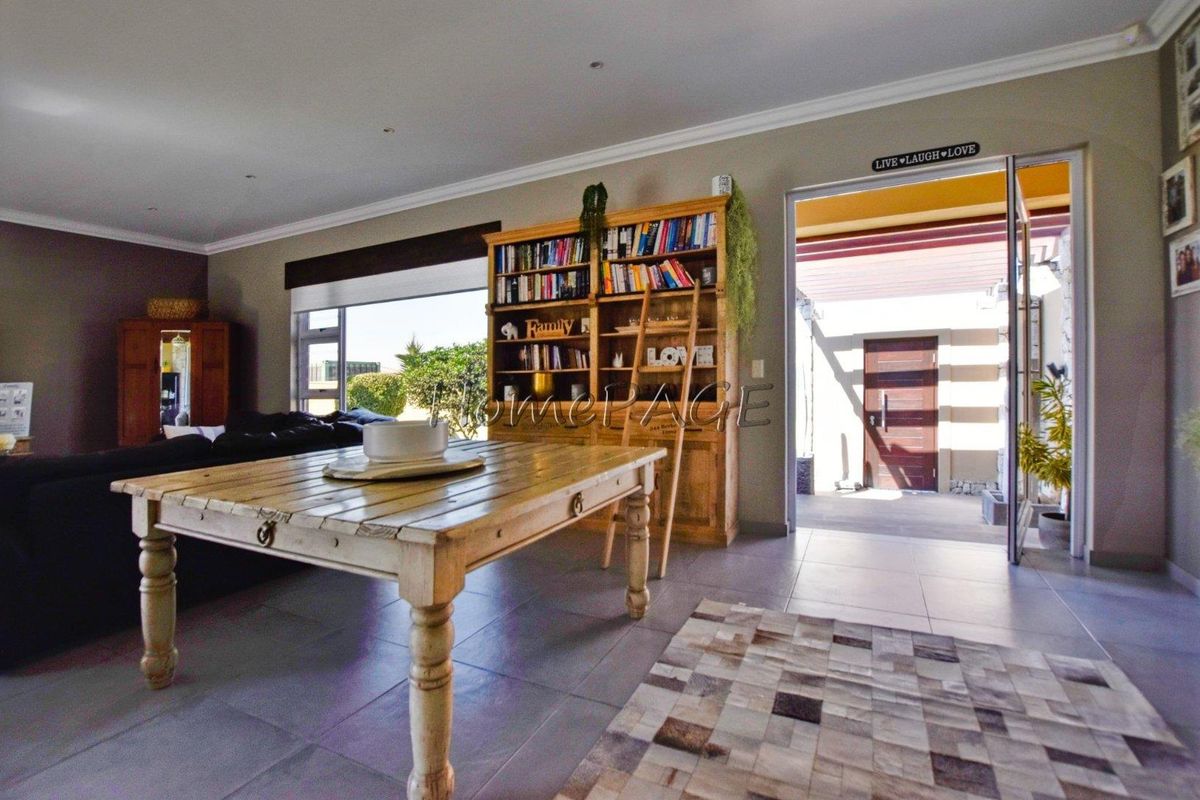 Spacious living area featuring large format floor tiles, recessed downlighting, and direct access to an outdoor patio through a wide doorway.