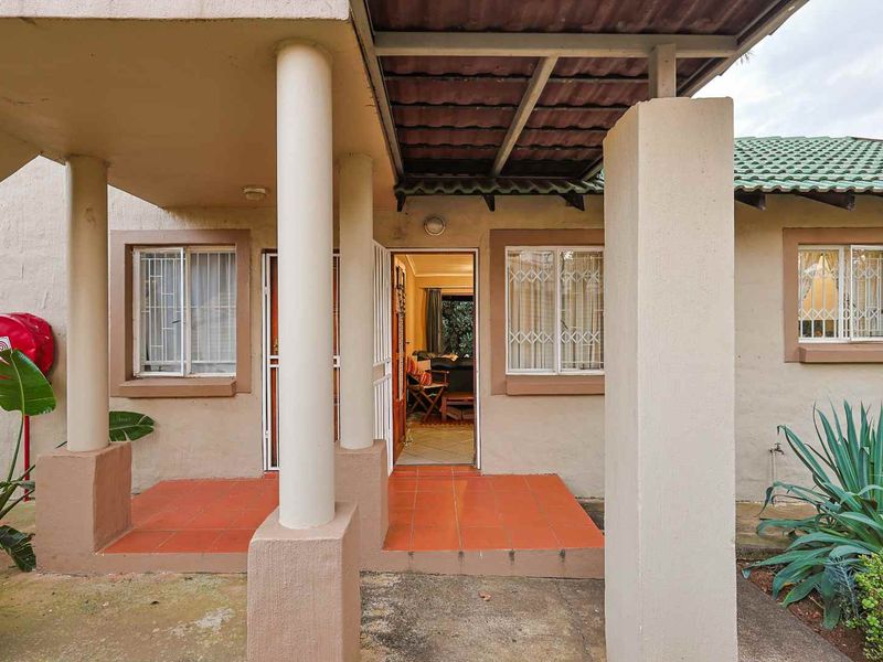 Covered entrance patio featuring tiled flooring, security gates, and structural columns, providing access to the main living area of the apartment.