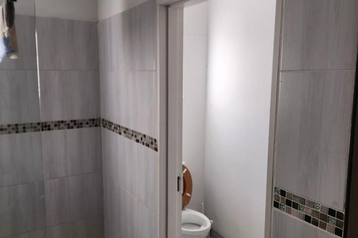 A bathroom featuring a walk-in shower with mosaic tile flooring and a separate enclosed toilet area with neutral wall tiling.
