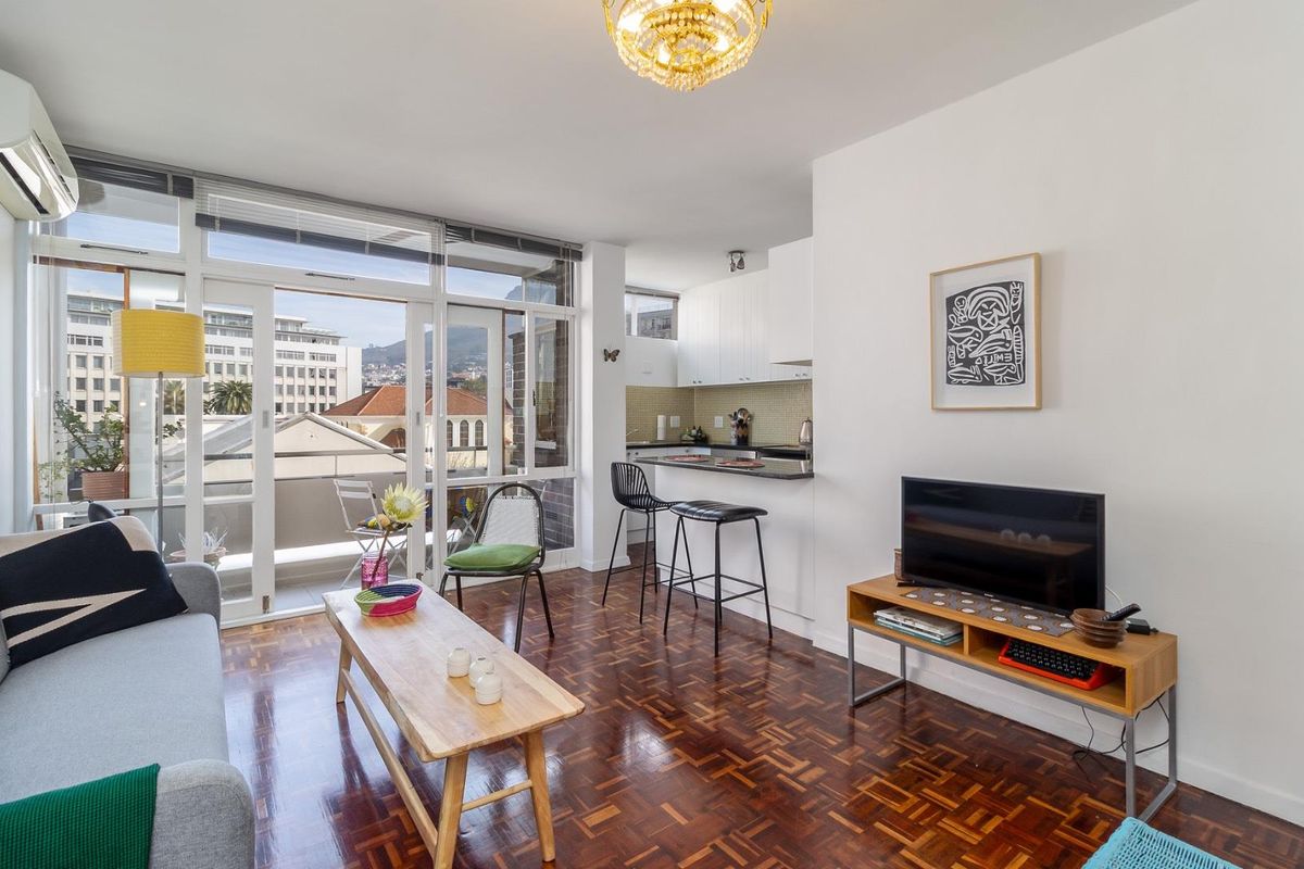 Open-plan living area featuring parquet flooring, a modern kitchen with granite countertops, and large glass sliding doors leading to a private balcony.