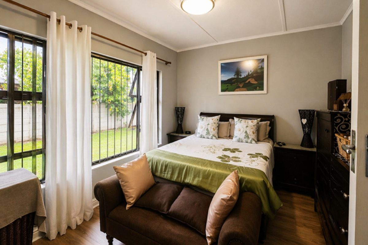 A well-maintained bedroom featuring laminate flooring, large windows with security bars, and neutral wall finishes, offering a comfortable and bright living space.
