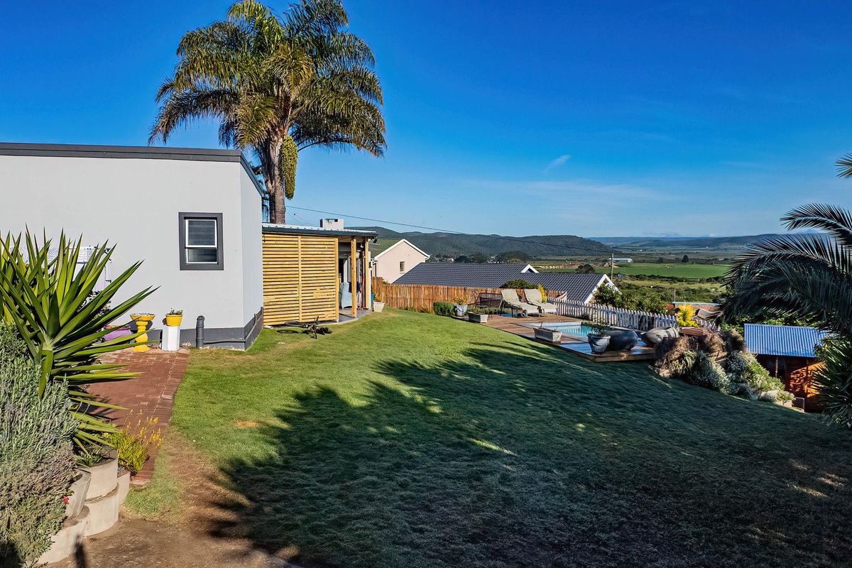 Rear garden featuring a swimming pool, timber decking, and a privacy screen, offering expansive views of the surrounding landscape.