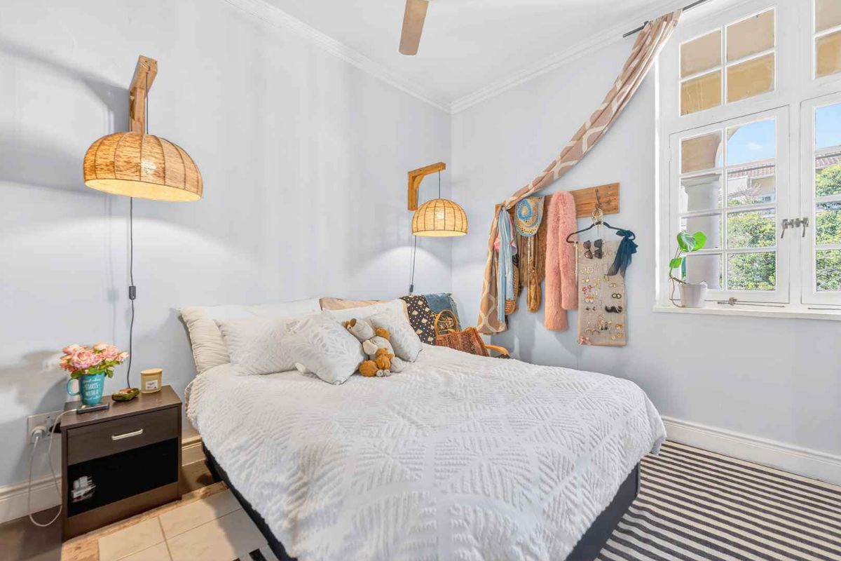 A well-lit bedroom featuring crown molding, a ceiling fan, and a large multi-pane window allowing for natural light.