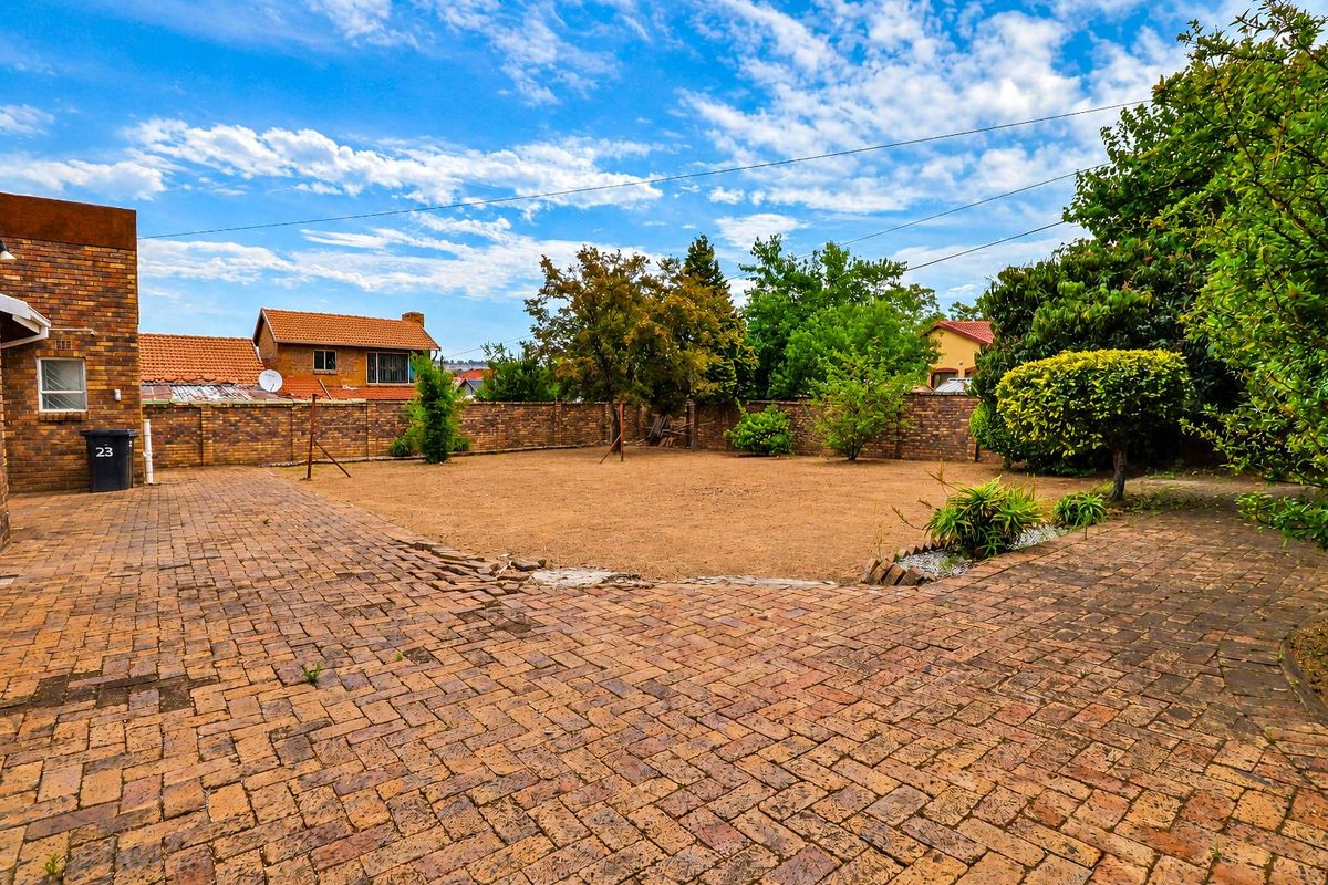 A spacious rear garden featuring extensive brick paving and a perimeter brick boundary wall, offering a private outdoor area.