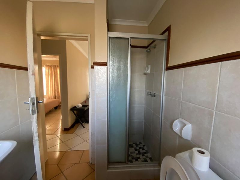A functional bathroom featuring a shower enclosure and tiled finishes, requiring cosmetic updates to modernize the space.
