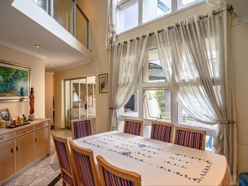Spacious dining area featuring double volume ceilings, large windows allowing ample natural light, and a mezzanine level overlooking the space.