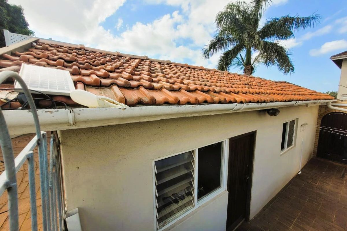 Exterior view of the rear building elevation featuring terracotta roof tiles, white guttering, and louvered windows.