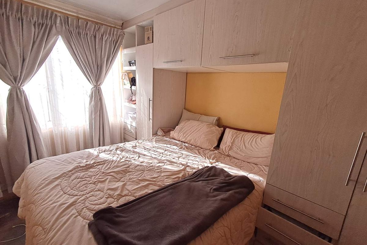 A bedroom featuring built-in light wood-grain cabinetry surrounding the bed area, providing integrated storage and shelving with natural light from the window.
