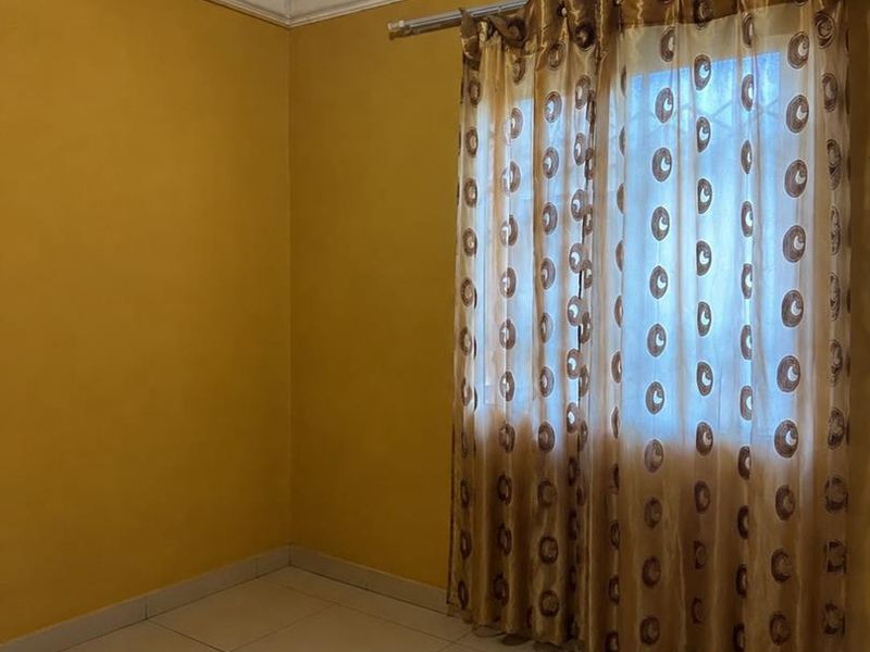 An empty bedroom featuring tiled flooring, yellow painted walls, and ceiling cornice detailing.