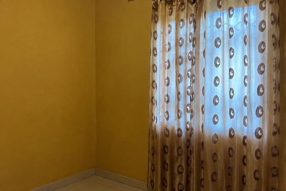 An empty bedroom featuring tiled flooring, yellow painted walls, and ceiling cornice detailing.