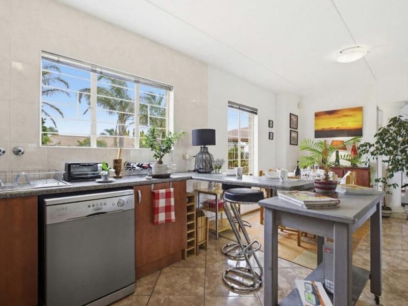Open plan kitchen and living area featuring tiled flooring, laminate countertops, and a breakfast bar, offering a functional and connected living space.