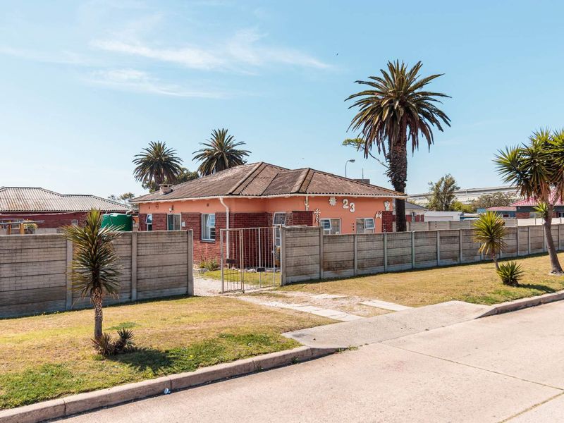 Front view of a single-story detached house featuring a brick and plaster facade, tiled roof, and a secure precast concrete boundary wall with gate.