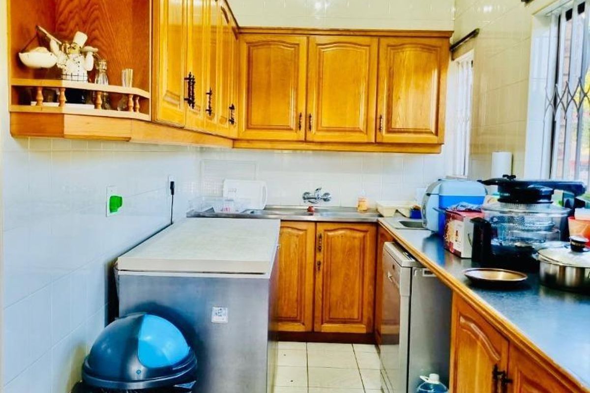 A functional kitchen featuring wooden cabinetry, tiled flooring, and a tiled backsplash, providing ample storage and workspace.