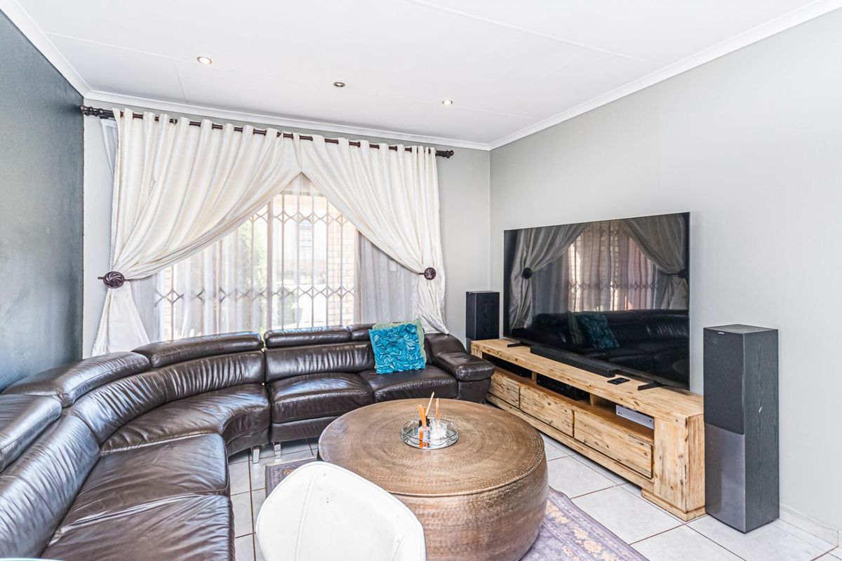 A well-maintained living room featuring tiled flooring, recessed ceiling lighting, and a security gate on the window.