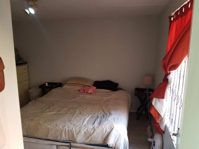 A functional bedroom featuring tiled flooring and a security gate on the window, providing a basic and practical living space.