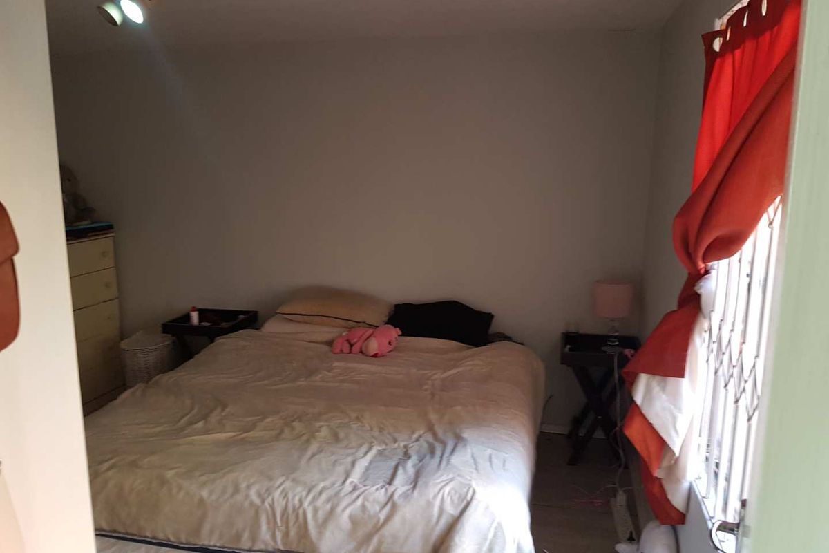 A functional bedroom featuring tiled flooring and a security gate on the window, providing a basic and practical living space.