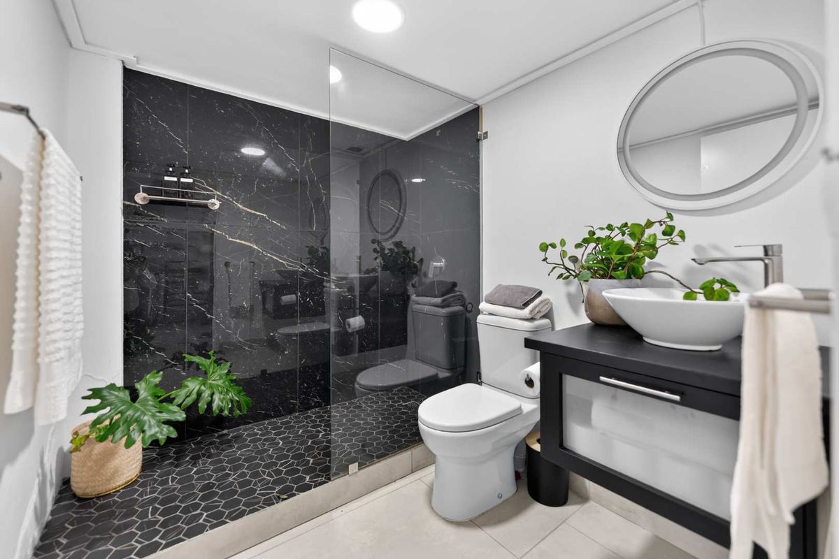 Modern bathroom featuring a walk-in shower with black marble-look tiles, hexagonal floor tiling, a sleek vanity with vessel sink, and contemporary fixtures.