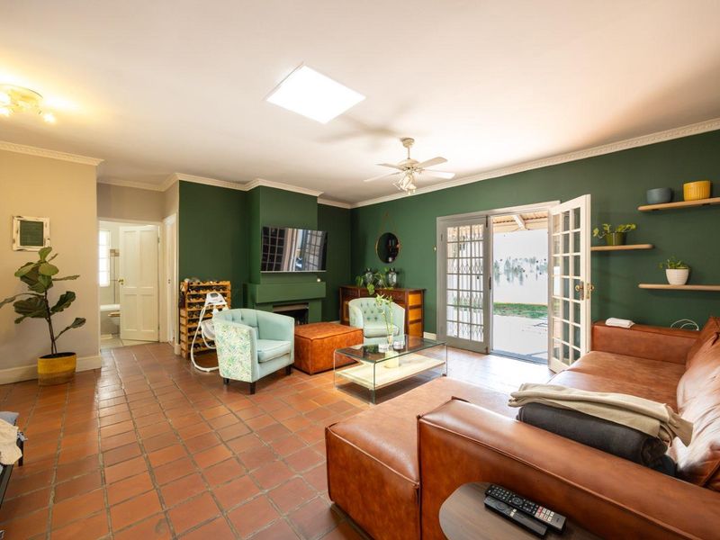 Spacious living room featuring terracotta tile flooring, a fireplace, a skylight, and direct access to the outdoor area through classic french doors.