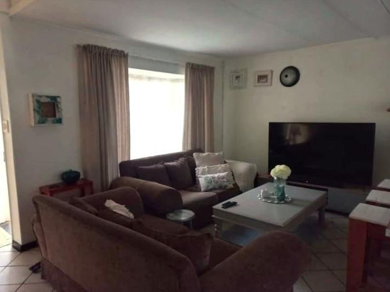A comfortable living room featuring tiled flooring and natural light from a large window, providing a functional space for relaxation.