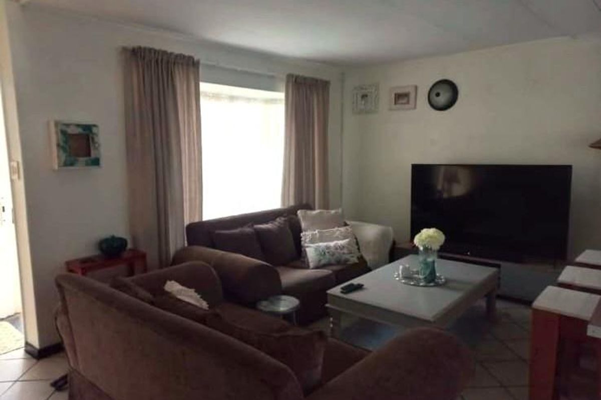 A comfortable living room featuring tiled flooring and natural light from a large window, providing a functional space for relaxation.