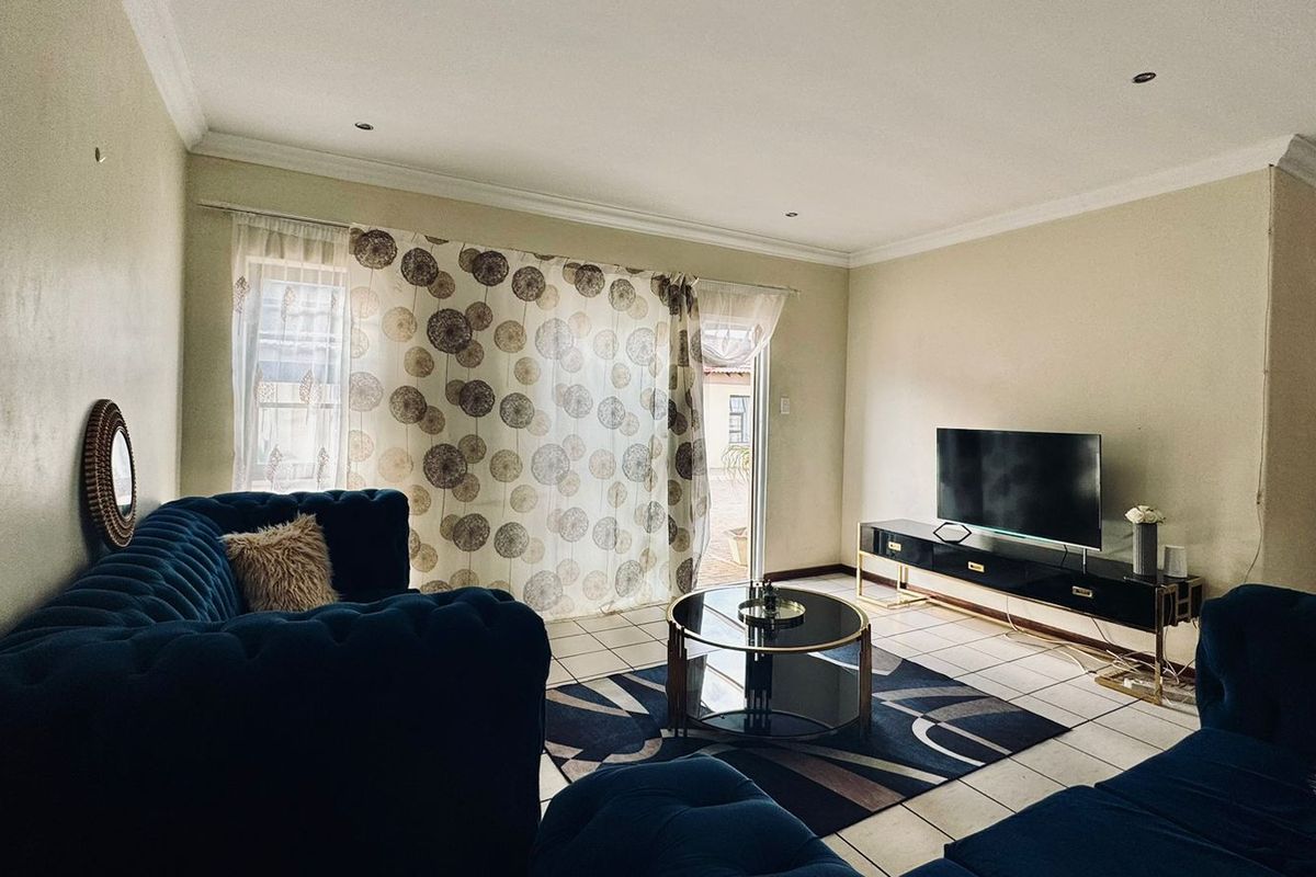 A living room featuring tiled flooring, recessed downlighting, and a sliding glass door providing access to the exterior.
