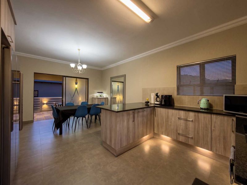 Open-plan kitchen and dining area featuring modern laminate cabinetry, granite countertops, under-cabinet lighting, and direct access to an outdoor patio through sliding glass doors.