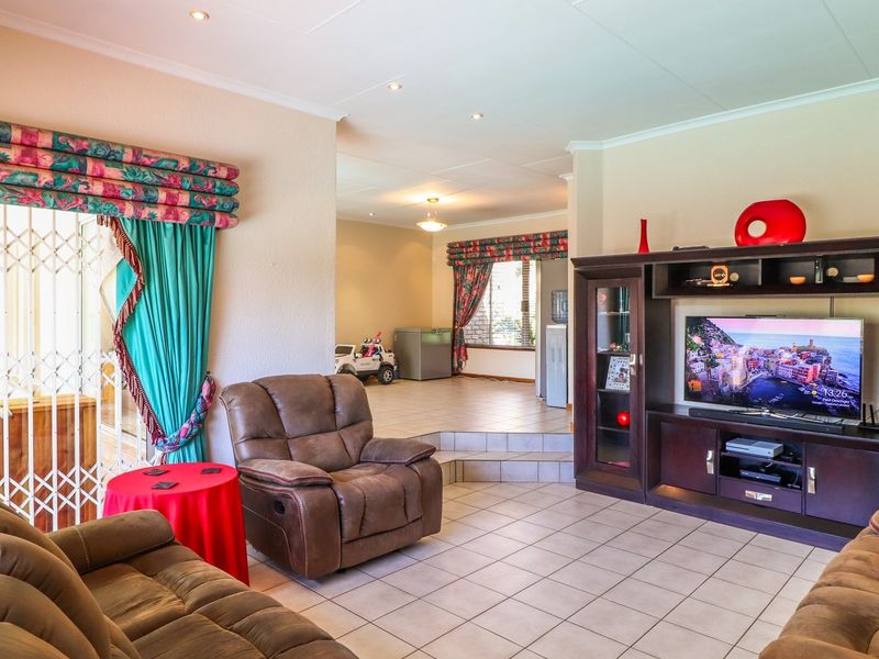 Spacious open-plan living area featuring tiled flooring, recessed lighting, and a split-level layout connecting to an adjacent room.