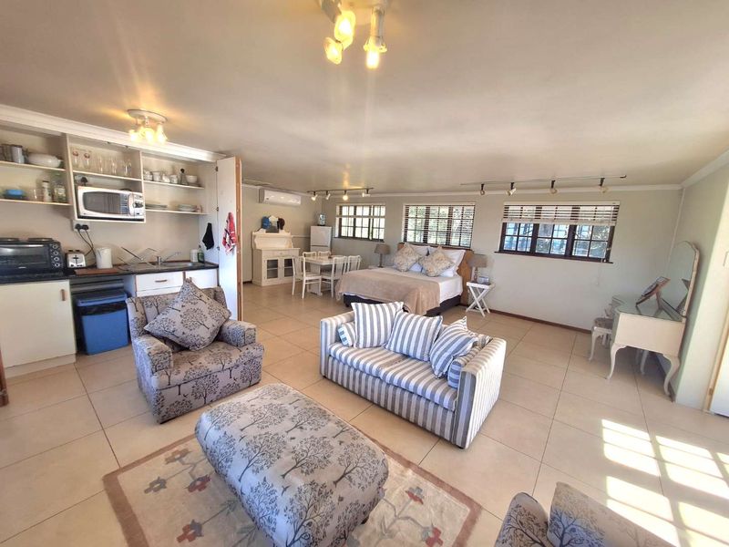 Spacious open-plan studio apartment featuring a kitchenette, tiled flooring, and large windows, offering a versatile living and sleeping area.