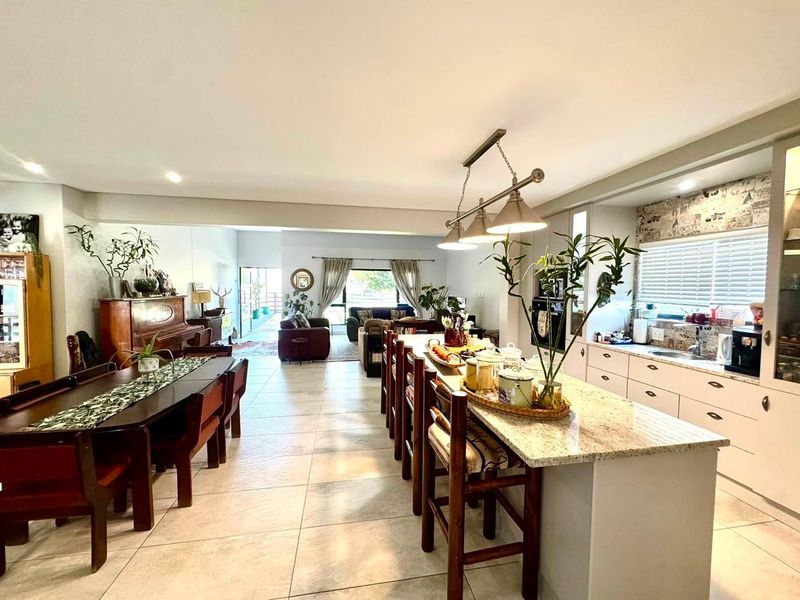 Spacious open-plan living area featuring a modern kitchen with a large island, granite countertops, and integrated appliances, flowing into the dining and lounge spaces.