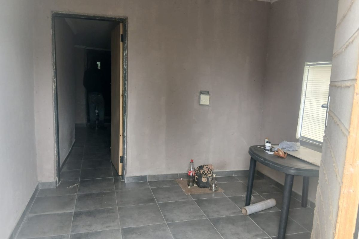 An unfinished living area featuring grey tiled flooring and raw plaster walls, offering a blank canvas for renovation and interior design.