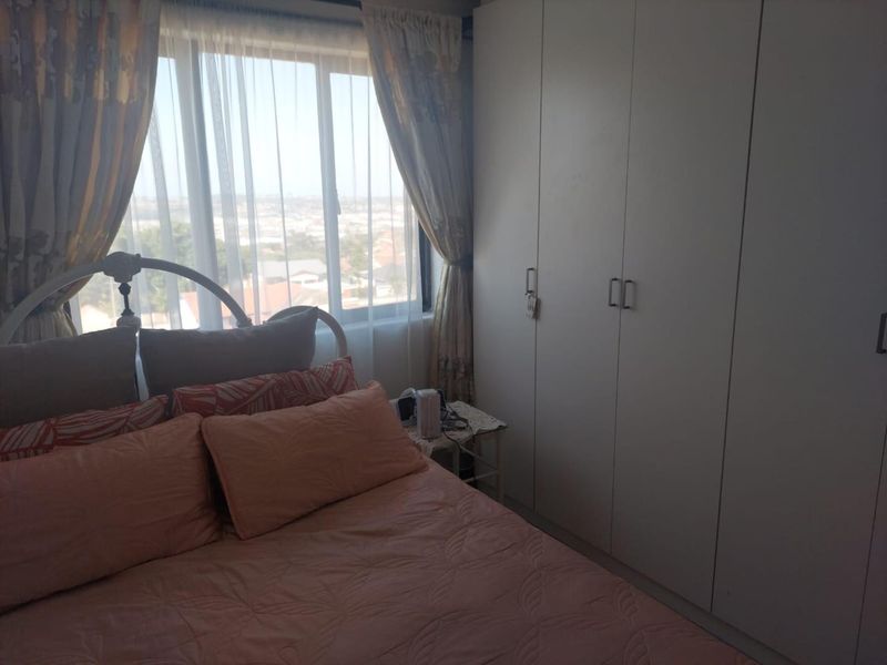 A bedroom featuring built-in cupboards and a large window providing natural light and an elevated view.