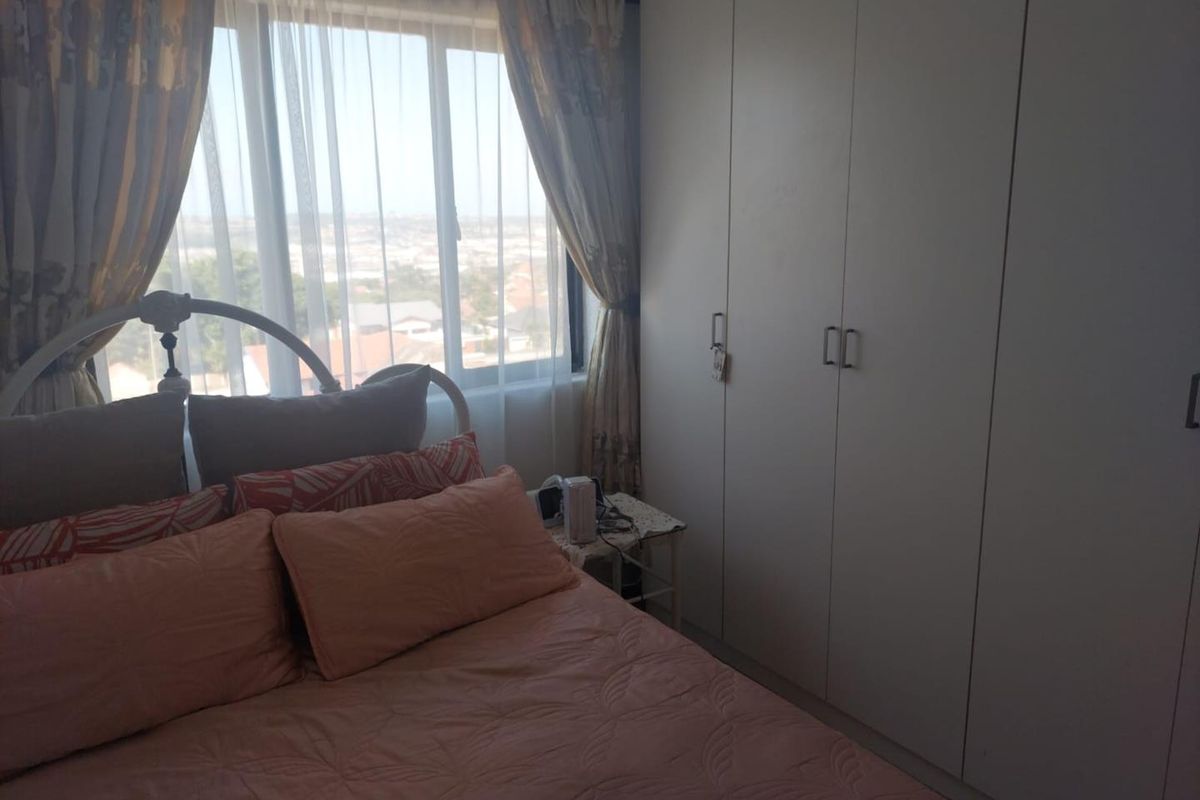A bedroom featuring built-in cupboards and a large window providing natural light and an elevated view.